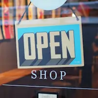An open sign in front of a glass door.